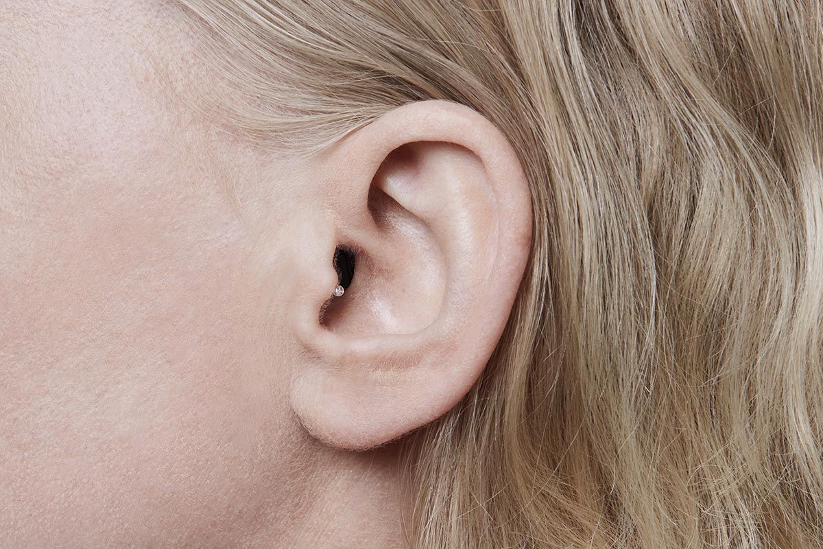 Invisible hearing aid inside woman's ear canal