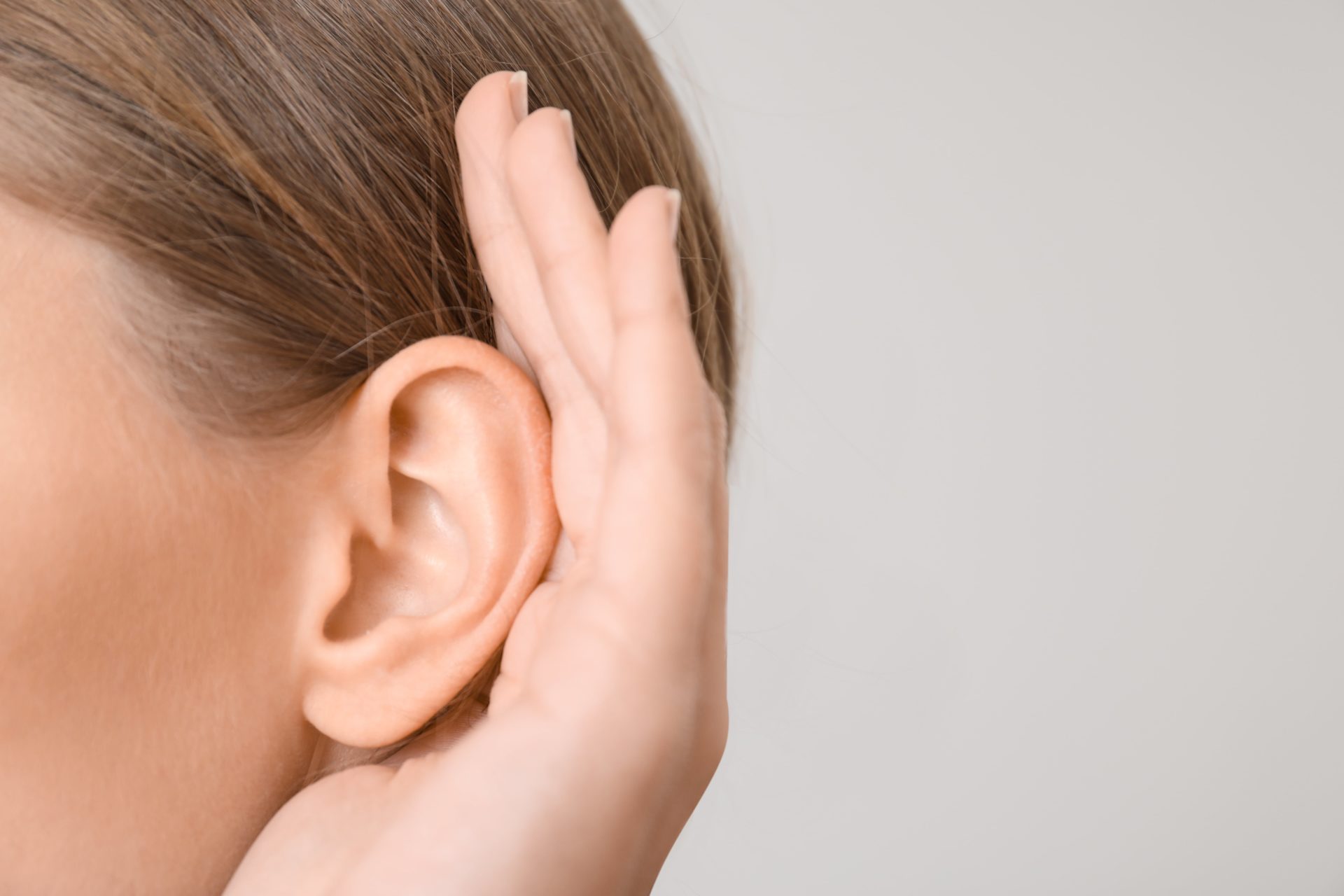 woman trying to hear through blocked ear, in need of microsuction ear wax removal