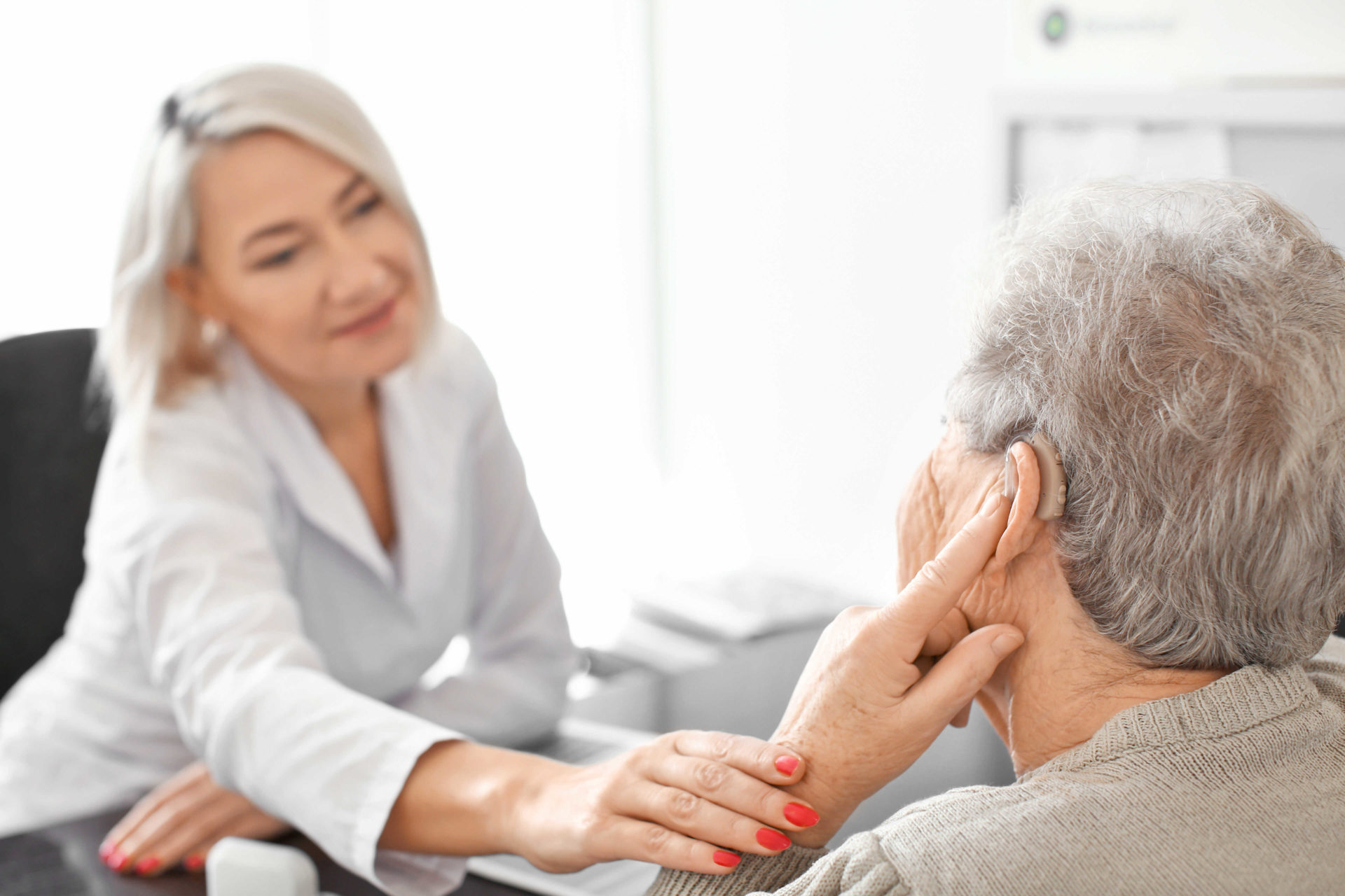 women being consulted about her hearing aid by a professional audiologist 