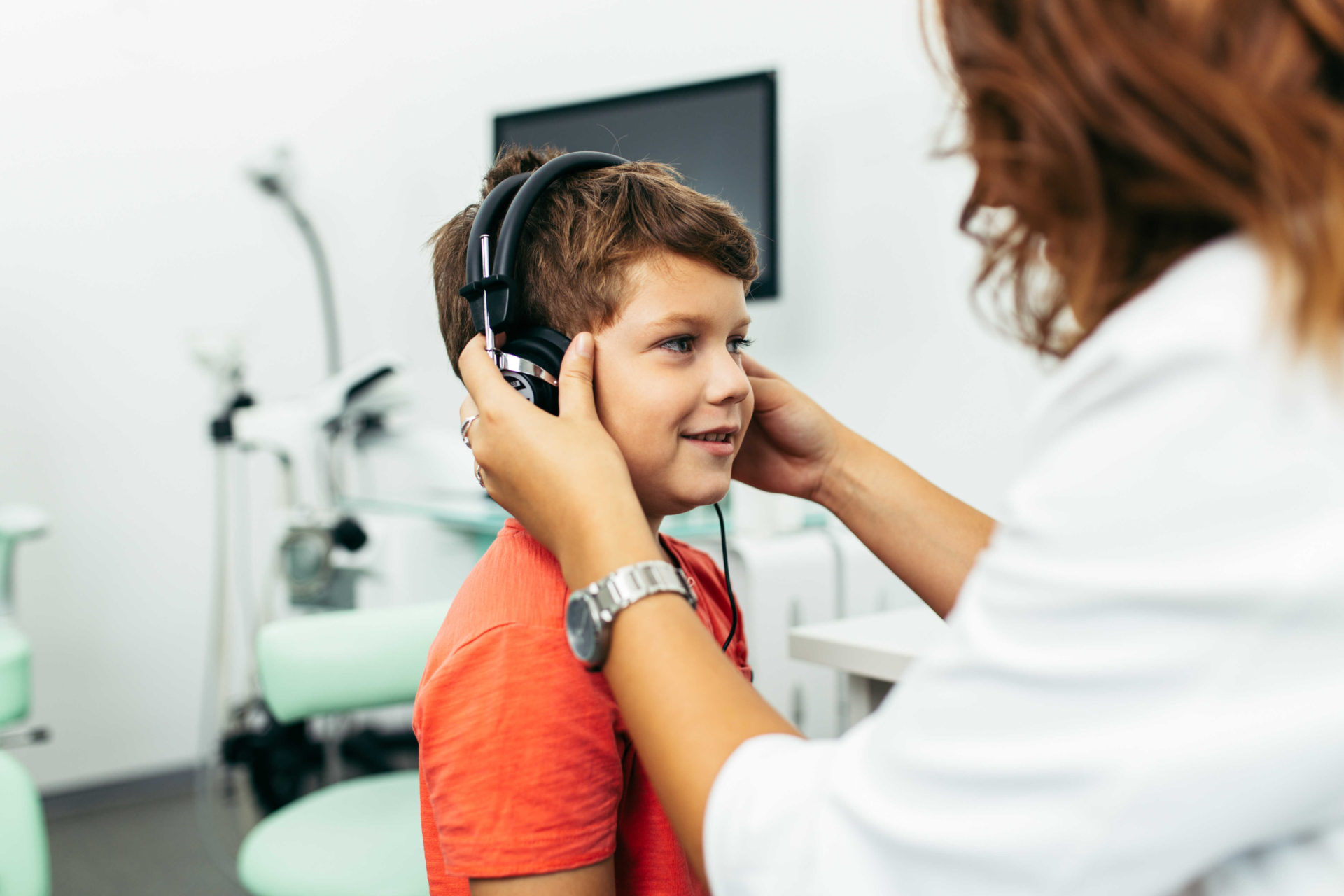 child being given headphones in preparation for hearing test by a professional audiologist
