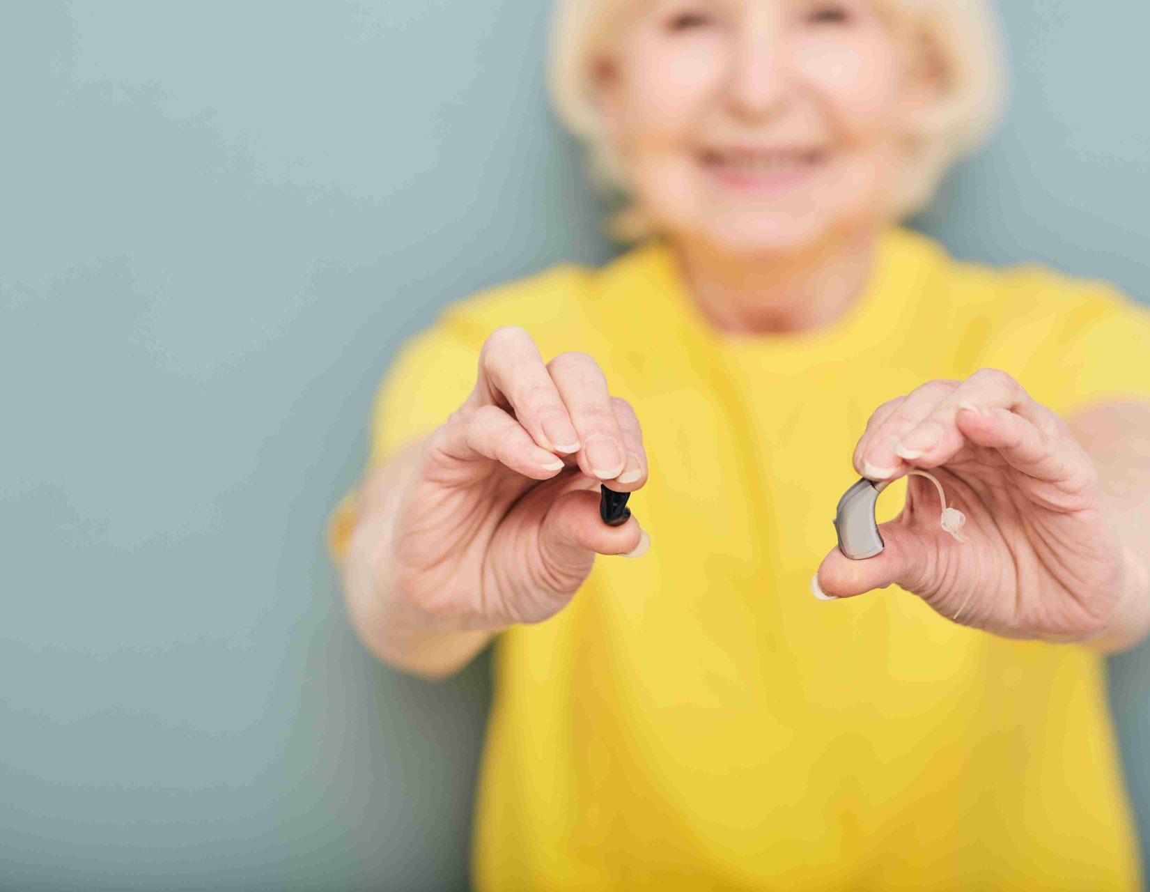 woman holding two different types of hearing aids