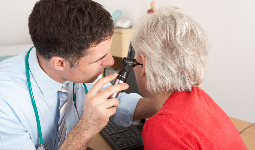 audiologist checking senior woman's ears