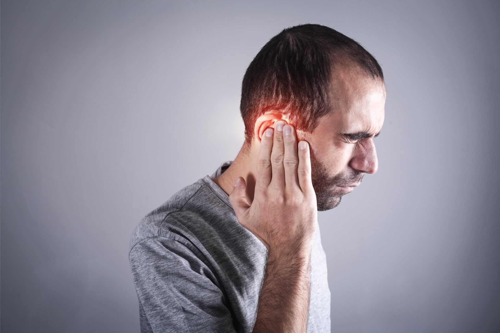 man experiencing tinnitus symptoms - buzzing noise in ear