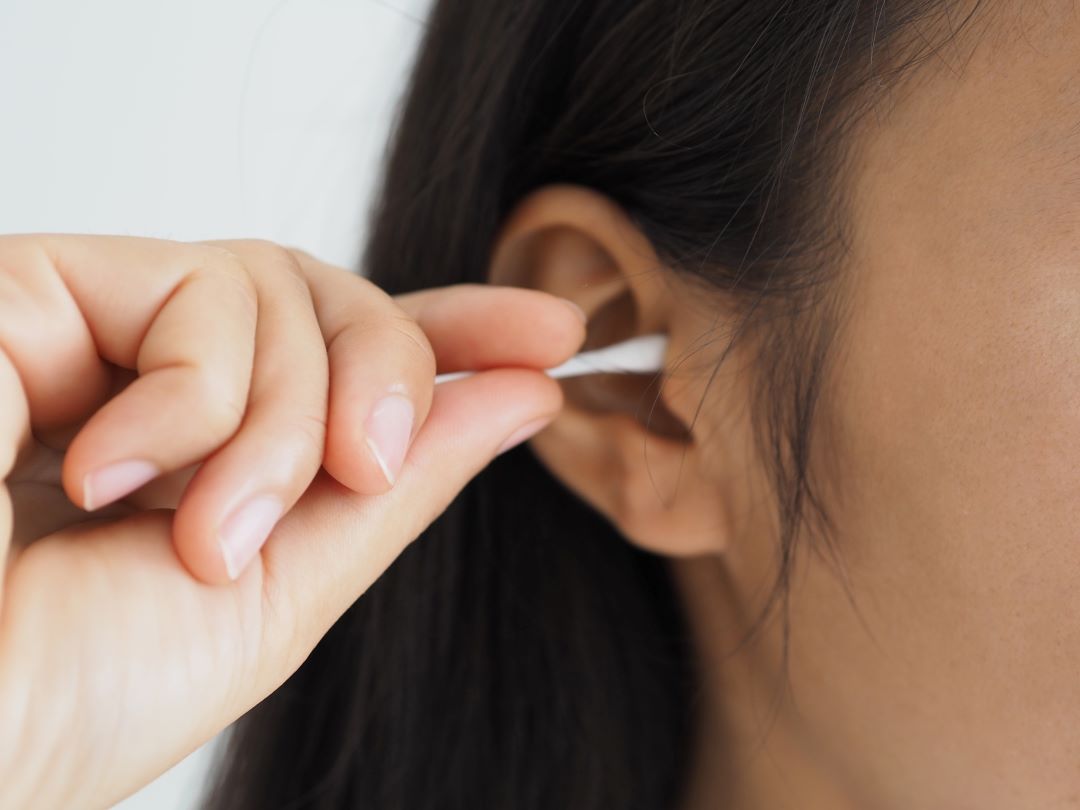 someone cleaning their ear with a cotton bud