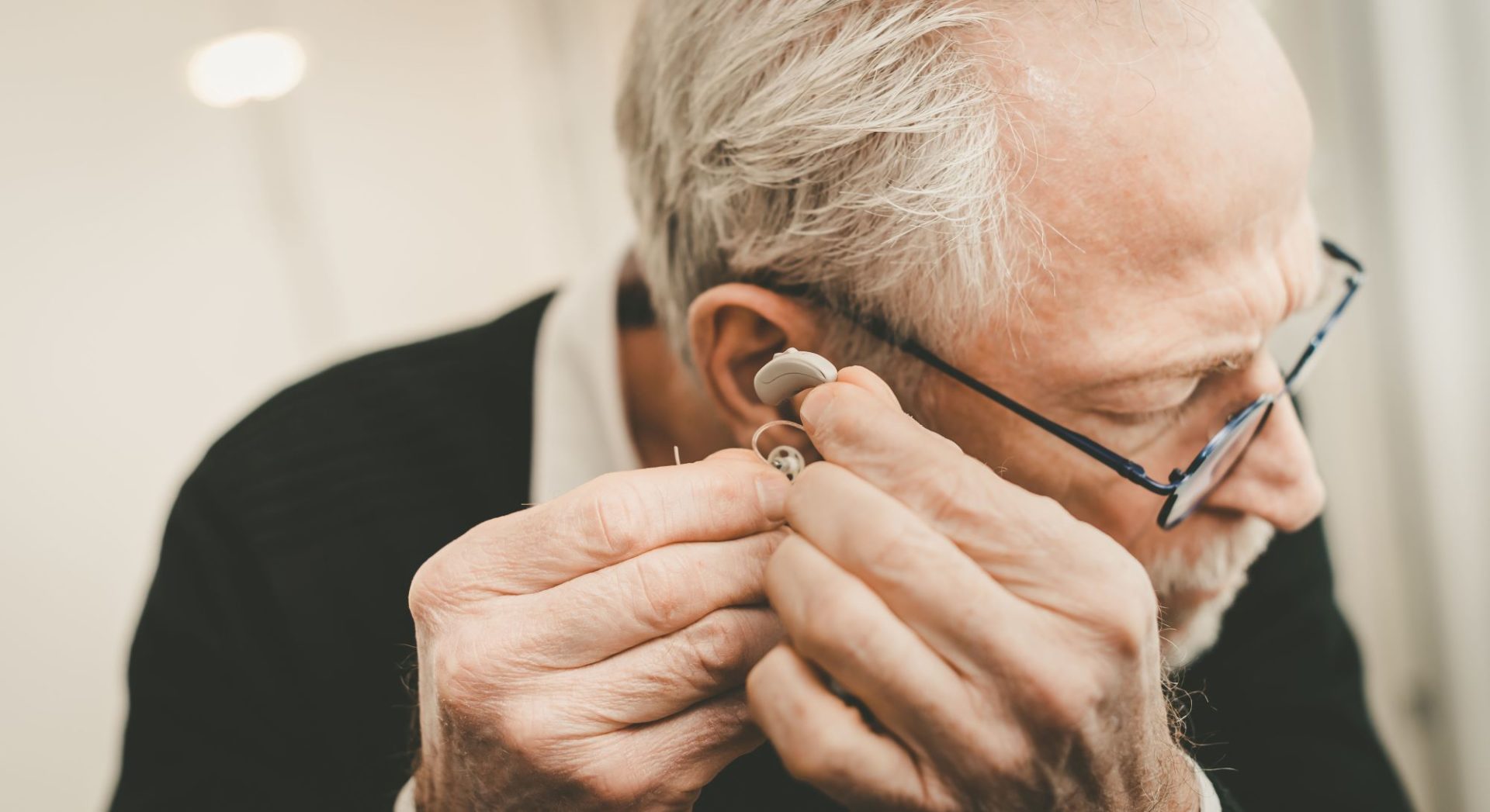 Old man putting on his hearing aids