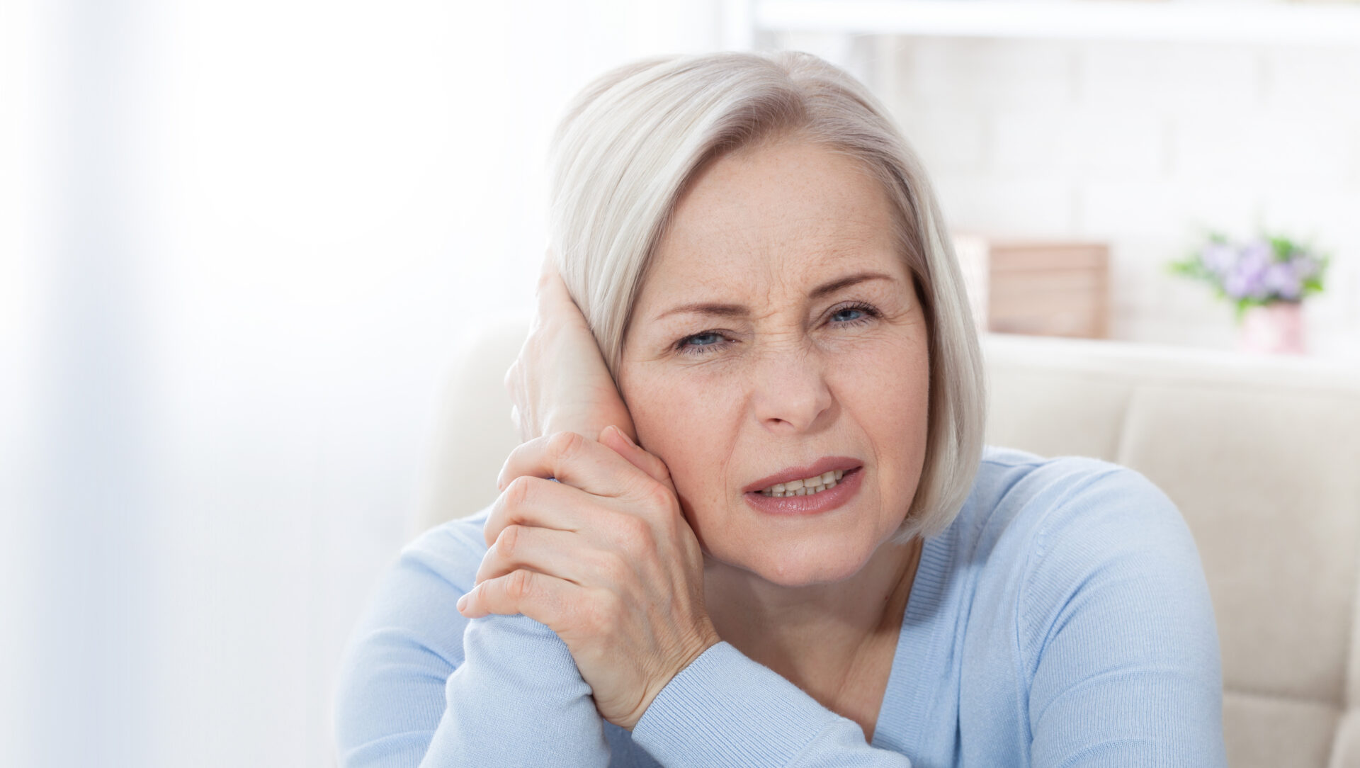 A woman holding her left ear in pain.