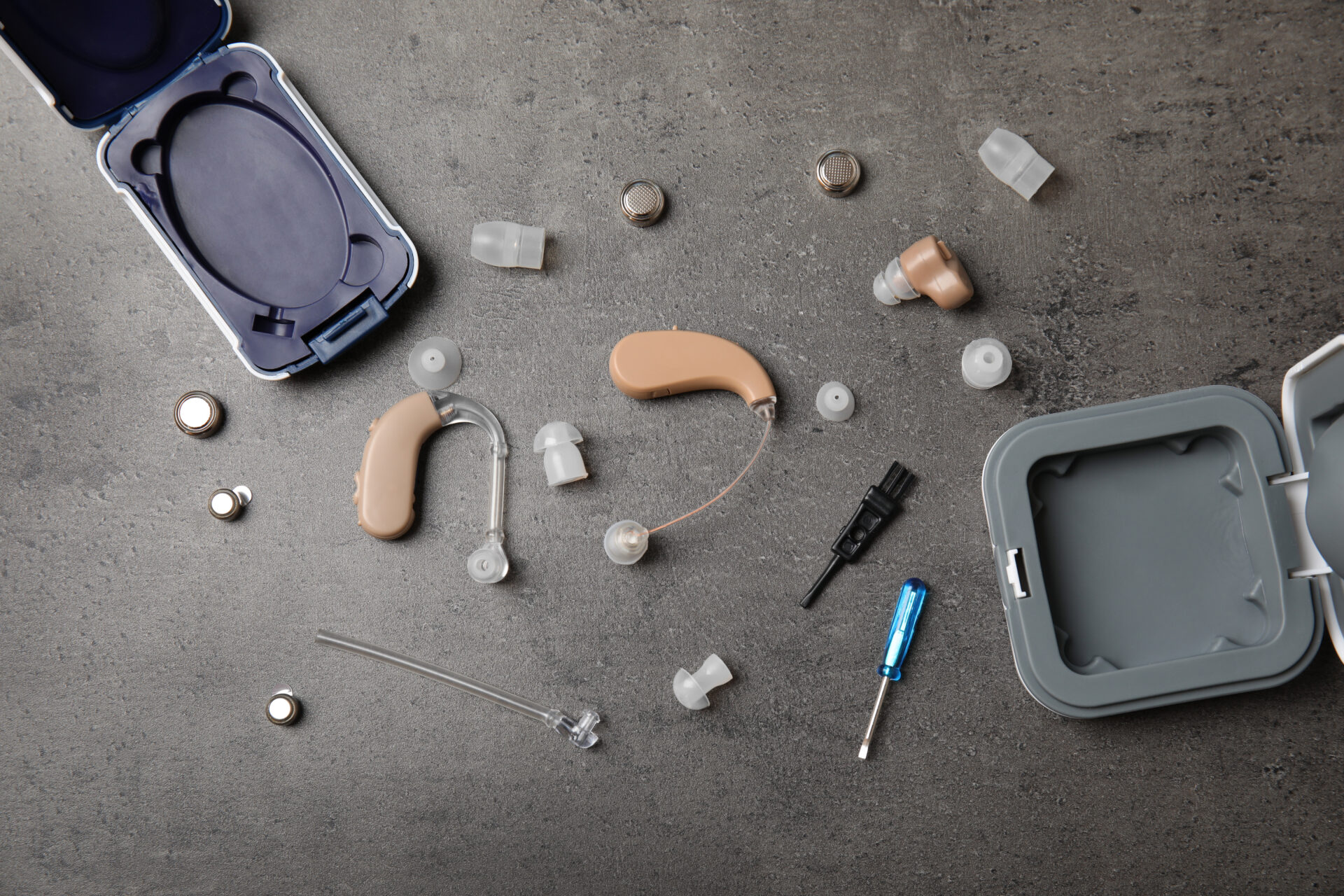 Flat lay composition with hearing aids and accessories on grey background