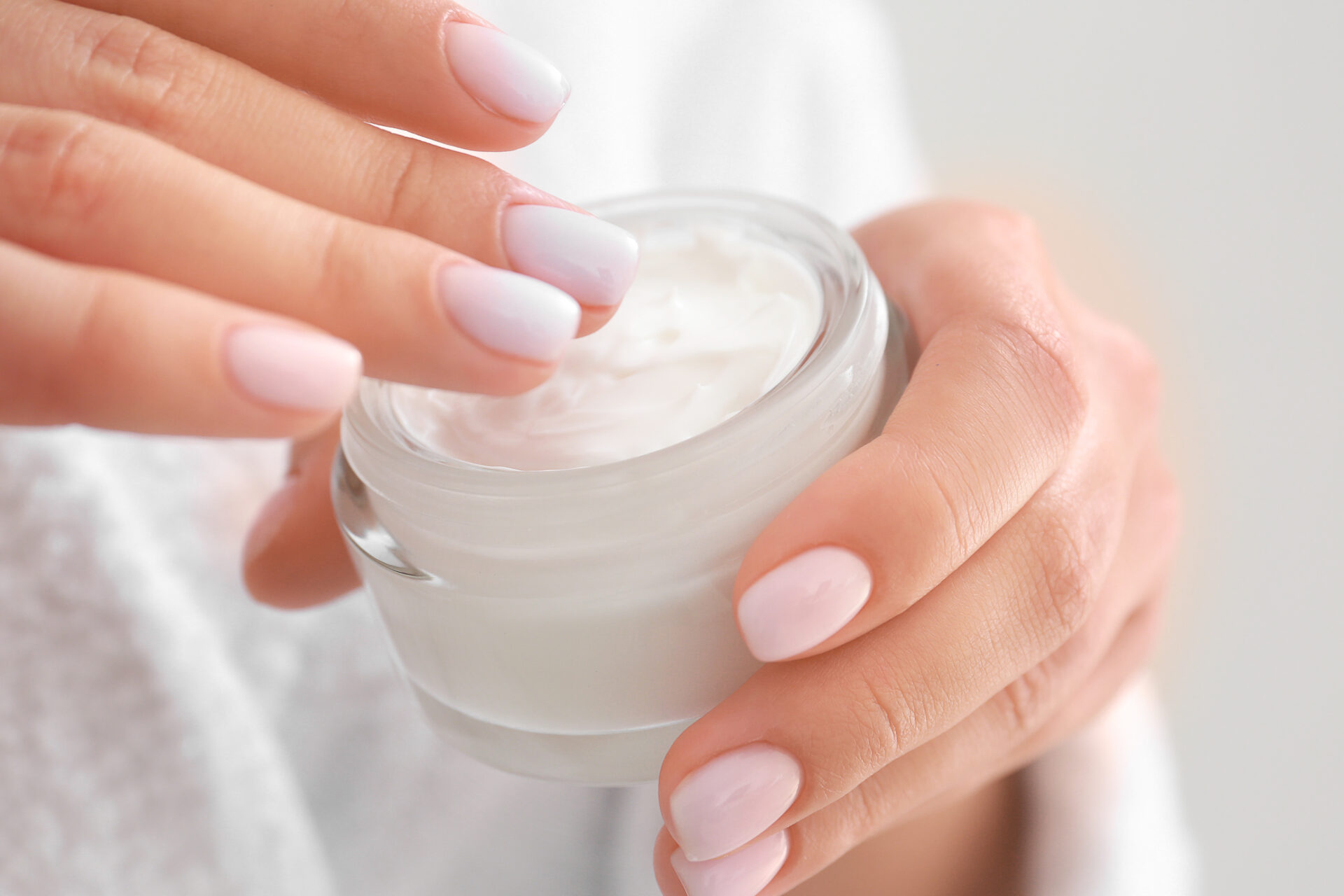 Woman with jar of cosmetic cream, closeup.